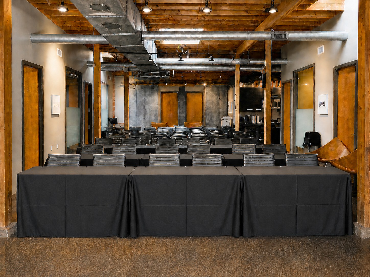 GeniusDen arranged with black-clothed tables and black-and-chrome chairs for a meeting or event