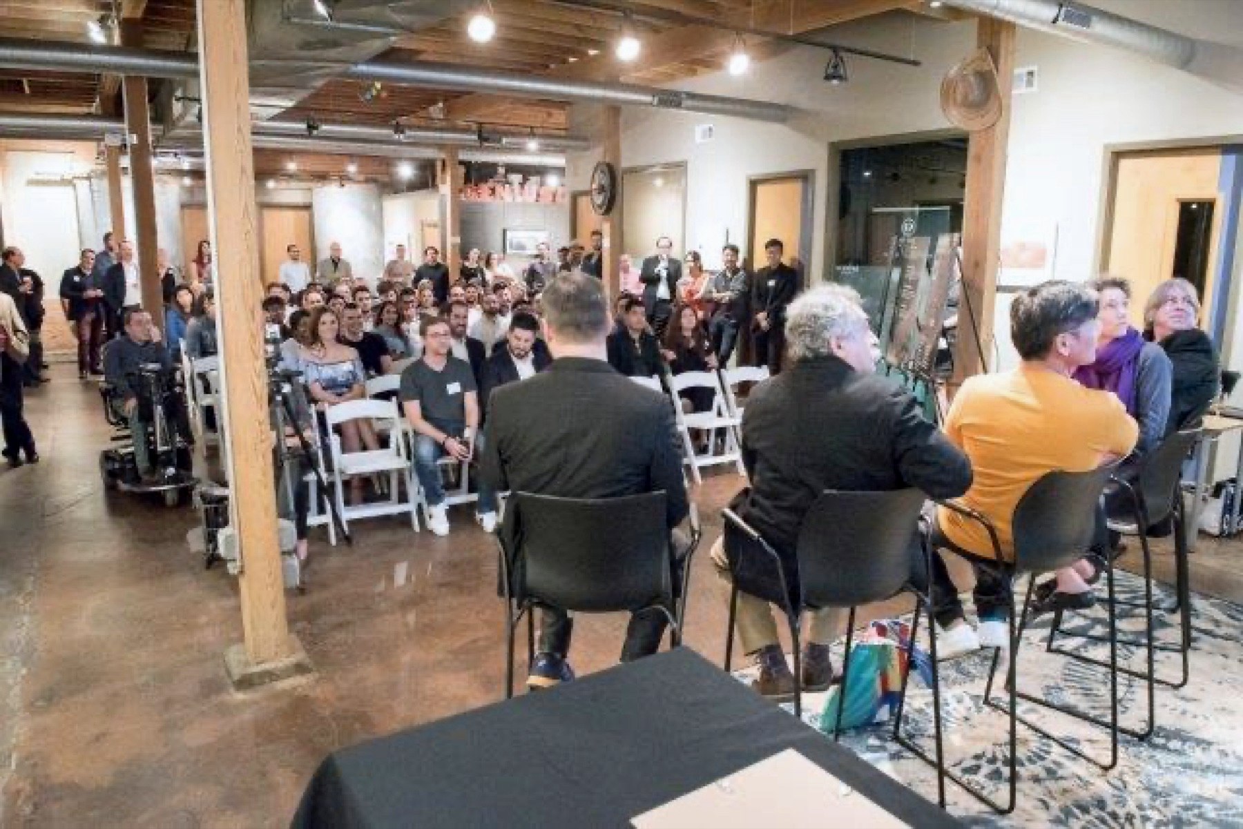 A GeniusDen panel event viewed from the front toward the audience